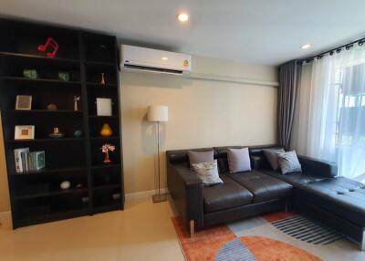 Modern living room with black leather sofa and wall-mounted air conditioning