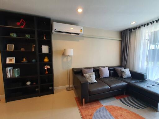 Modern living room with black leather sofa and wall-mounted air conditioning