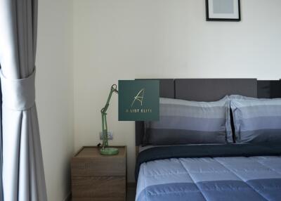 Modern bedroom with a neatly made bed, bedside table, and lamp