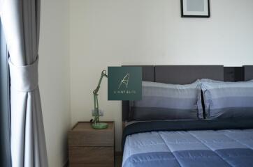 Modern bedroom with a neatly made bed, bedside table, and lamp