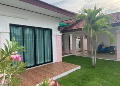 Exterior of a house with green lawn, palm tree, and porch