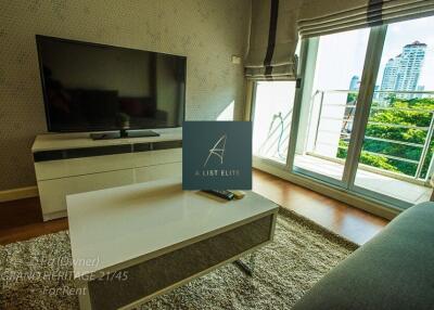 Modern living room with large TV, coffee table, and balcony view