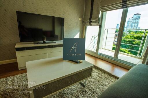 Modern living room with large TV, coffee table, and balcony view