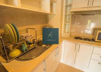 A modern kitchen with white cabinets, sink, stove, and dish rack.