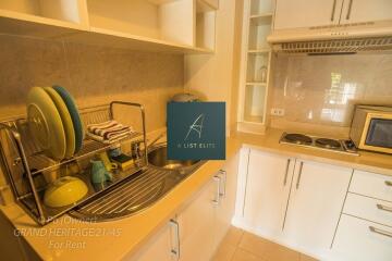 A modern kitchen with white cabinets, sink, stove, and dish rack.