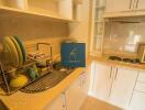 A modern kitchen with white cabinets, sink, stove, and dish rack.