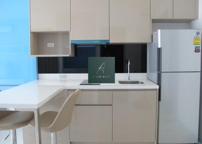 Modern kitchen with beige cabinets, white countertops, and a silver refrigerator