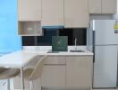 Modern kitchen with beige cabinets, white countertops, and a silver refrigerator