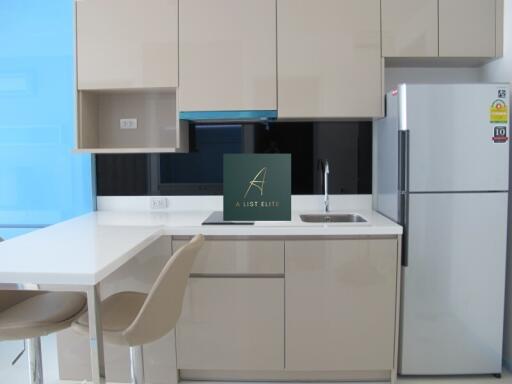 Modern kitchen with beige cabinets, white countertops, and a silver refrigerator