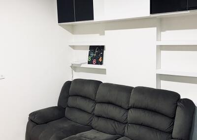 Living room with black couch and wall shelves