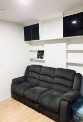 Living room with black couch and wall shelves