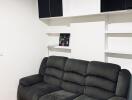 Living room with black couch and wall shelves