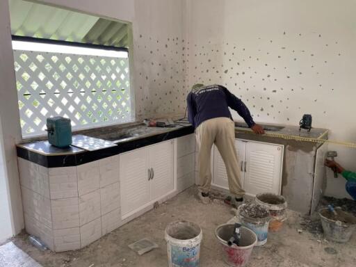 Partially renovated kitchen with worker