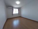 Empty bedroom with wooden flooring and large window