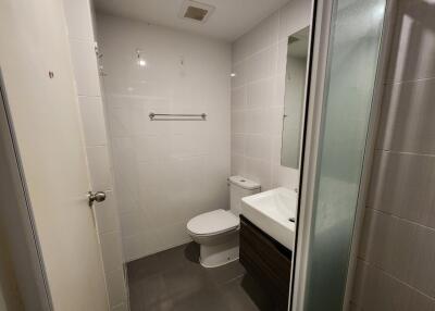 Modern bathroom with tiled floor and walls, featuring a toilet, sink, and shower area