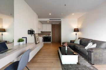 Modern living area with sofa, coffee table, work desk, and kitchen