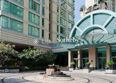 Exterior view of a residential building with modern architecture featuring a fountain and landscaped entrance