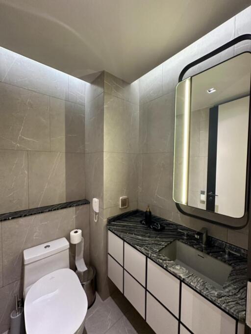 Modern bathroom with illuminated mirror and marble countertop