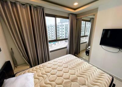 Bedroom with large window, TV, curtains, and bed