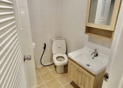 Compact modern bathroom with toilet, sink, and mirror