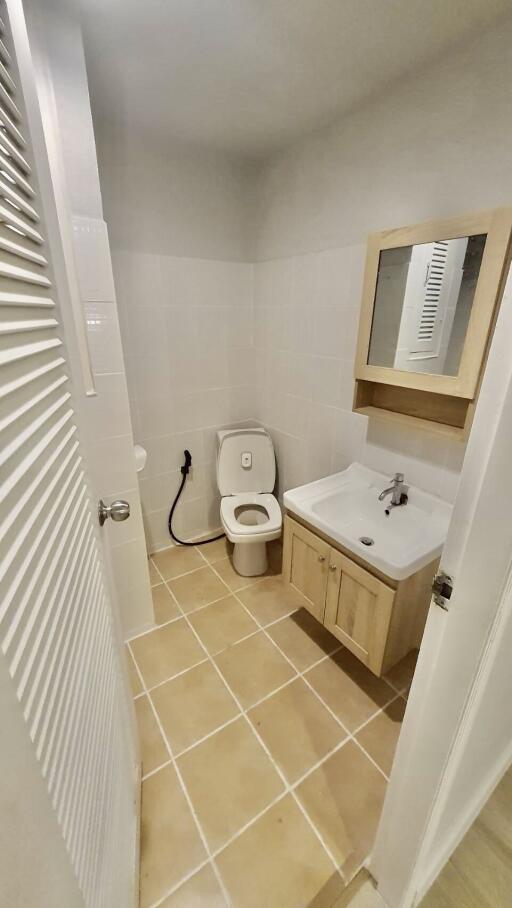 Compact modern bathroom with toilet, sink, and mirror