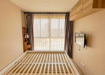 Modern bedroom with empty bed frame, wall-mounted TV, and large window