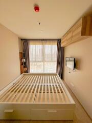 Modern bedroom with empty bed frame, wall-mounted TV, and large window