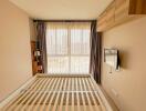 Modern bedroom with empty bed frame, wall-mounted TV, and large window