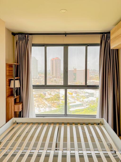 A bedroom with a large window overlooking a cityscape.