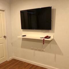 Wall-mounted TV with shelf in a living room