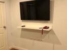 Wall-mounted TV with shelf in a living room