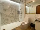 Modern bathroom with marble walls, large mirror, and glass shower enclosure