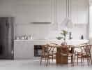 Modern kitchen with white cabinets, stainless steel fridge, wooden dining table and chairs, and pendant lighting