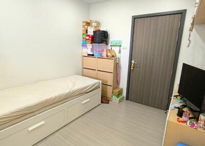 Neat and compact bedroom with single bed, storage, and television.