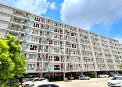 Exterior view of a multi-story residential building with parking area