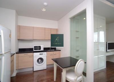 Modern kitchen with wooden cabinets, integrated washing machine, refrigerator, and adjacent work area