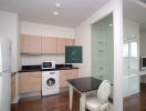 Modern kitchen with wooden cabinets, integrated washing machine, refrigerator, and adjacent work area