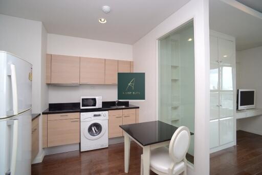 Modern kitchen with wooden cabinets, integrated washing machine, refrigerator, and adjacent work area