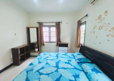 Bedroom with decorative leaves-patterned bedding, windows, and wardrobe