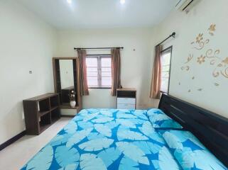 Bedroom with decorative leaves-patterned bedding, windows, and wardrobe