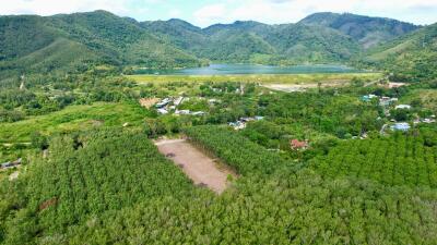 Aerial view of a green landscape with a lake and mountains in the background