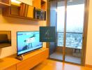 Living room with television and large glass door to balcony