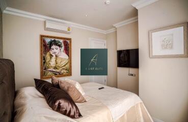 Cozy bedroom with decorative artwork, air conditioning, and a wall-mounted TV.