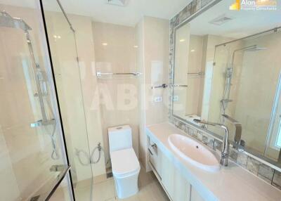 Modern bathroom with shower enclosure, toilet, and sink with large mirror