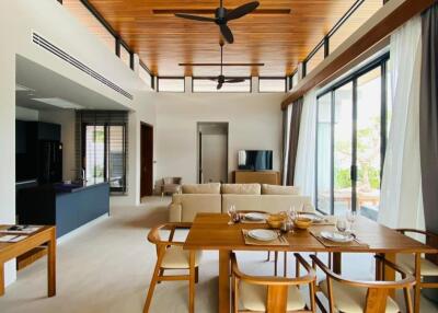 Modern open-plan living and dining area with wooden ceiling and large windows