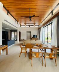 Modern open-plan living and dining area with wooden ceiling and large windows