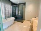 Modern bathroom with a bathtub, glass shower, and double sink vanity