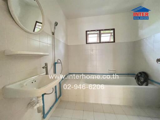 A clean bathroom with a bathtub, sink, mirror, and shower setup.