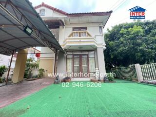 Front view of a house with a green artificial lawn and covered carport