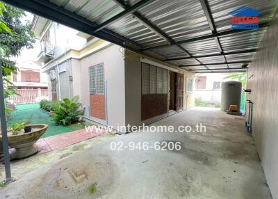 Covered outdoor area with adjacent house and small garden